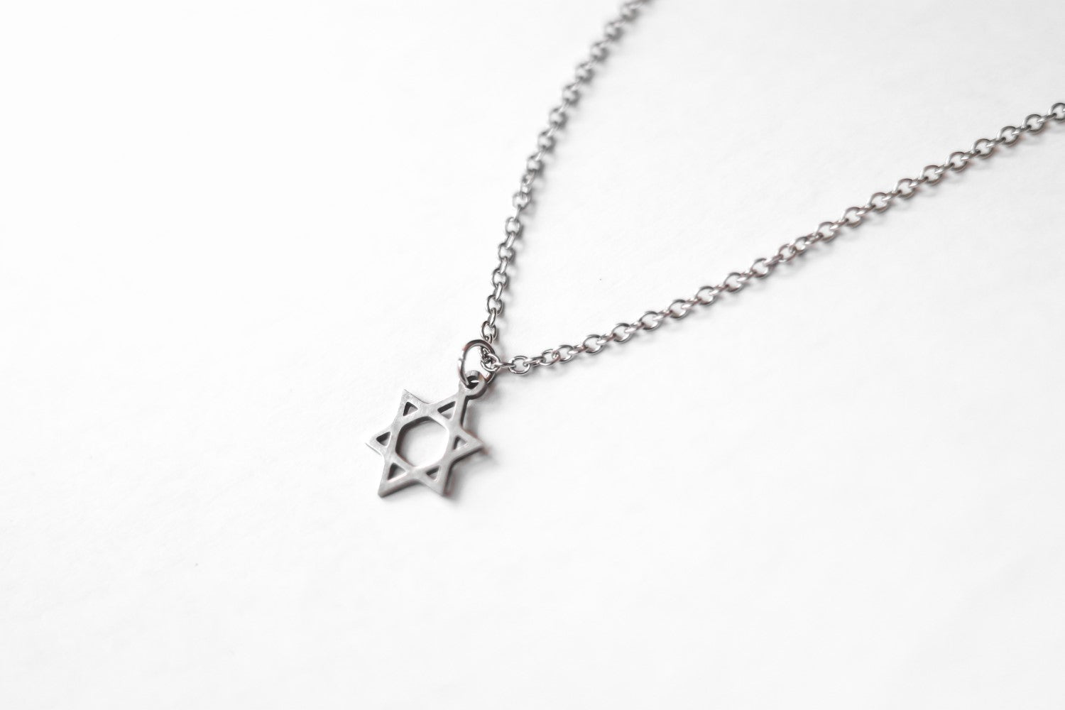 A silver Star of David necklace with a stainless steel chain, displayed against a white background.