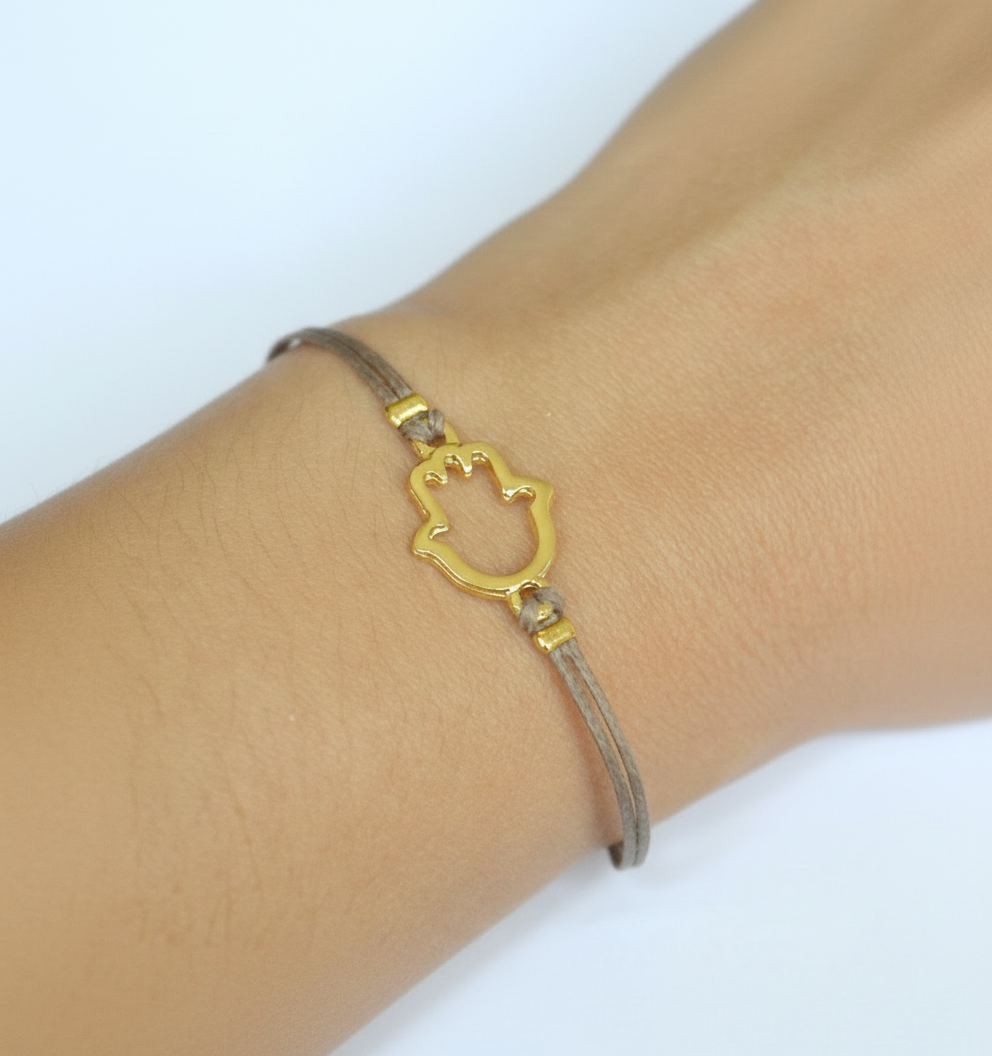 Bracelet with a gold Hans hand shaped clasp on a wrist against a white background