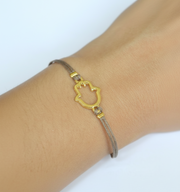 Bracelet with a gold Hans hand shaped clasp on a wrist against a white background