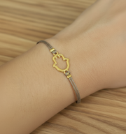 Bracelet with a gold cat-shaped hamsa clasp on a wrist against a wooden background