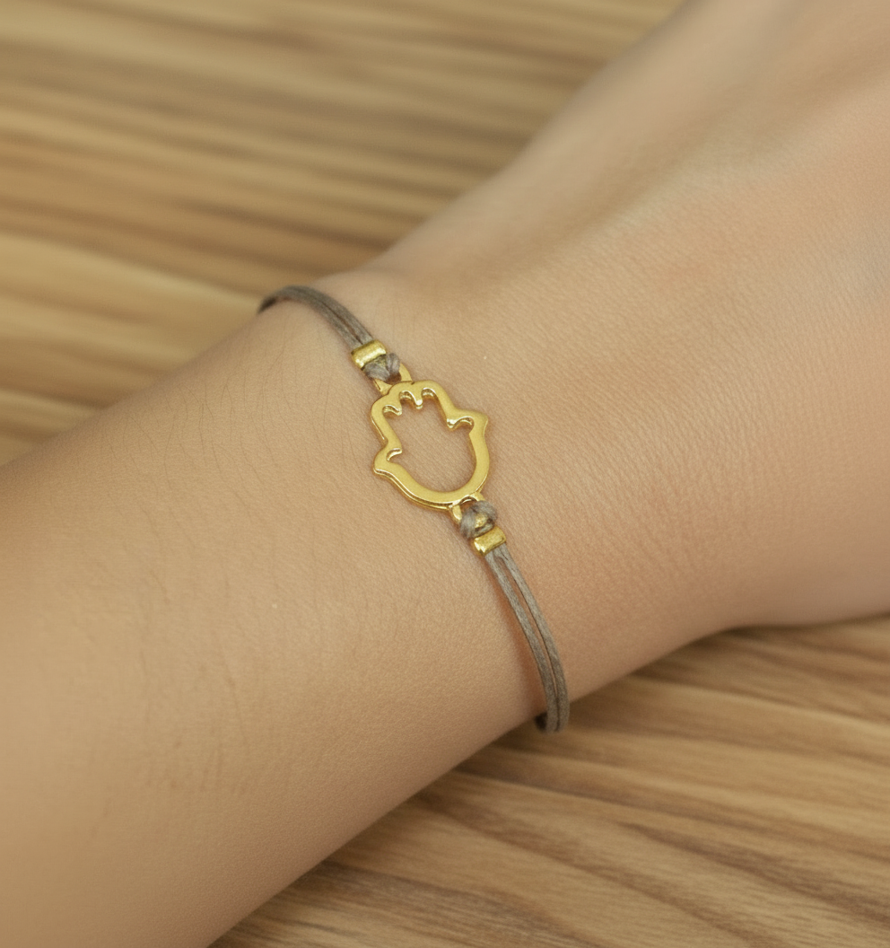 Bracelet with a gold cat-shaped hamsa clasp on a wrist against a wooden background