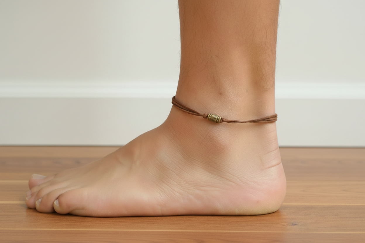 Ankle with a brown cord anklet on a wooden floor.