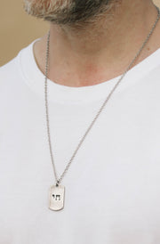 Person wearing a white t-shirt and a necklace with a chain jewish Star of David dog tag
