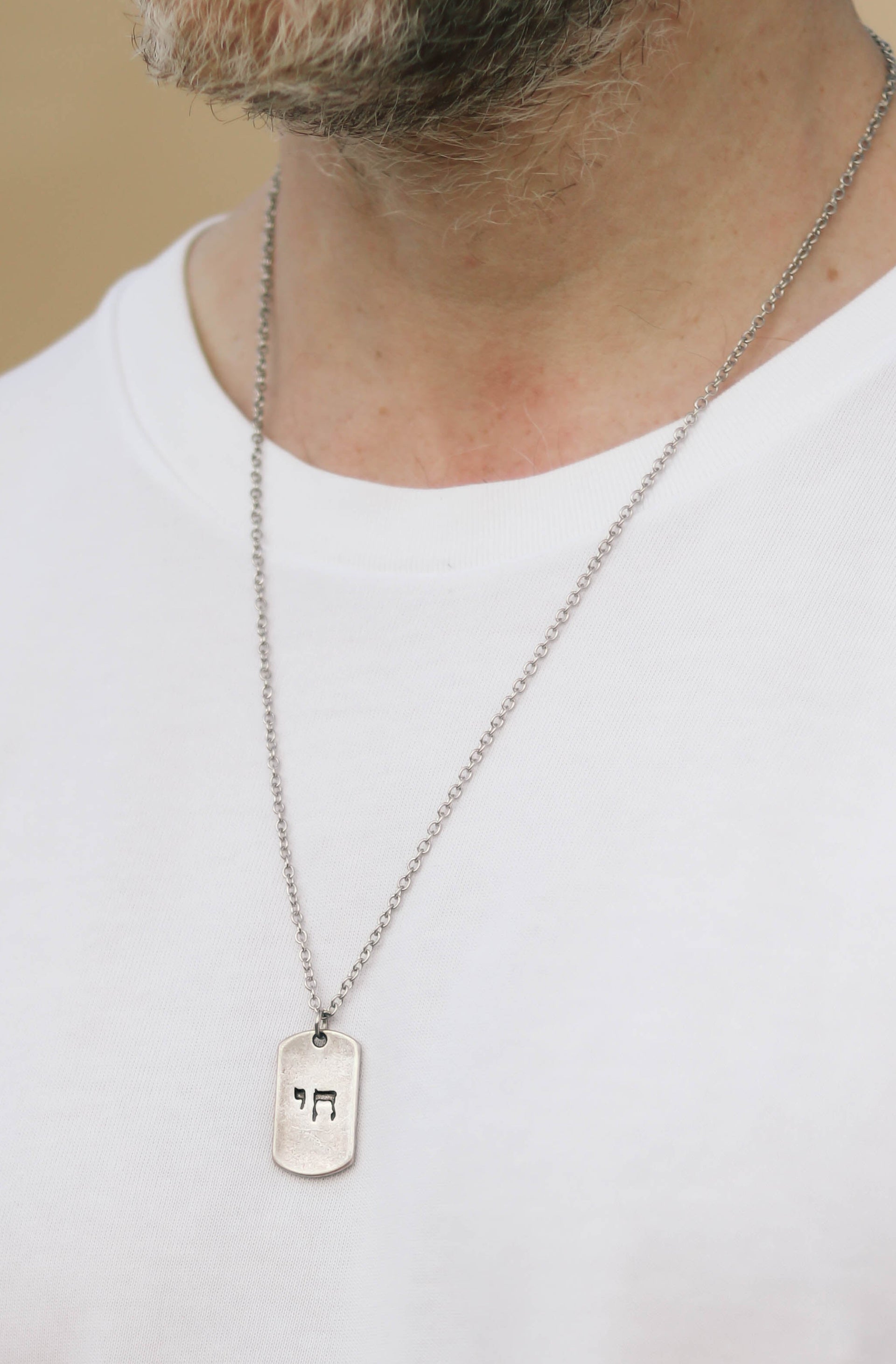 Person wearing a white t-shirt and a necklace with a chain jewish Star of David dog tag