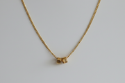 Gold necklace with a small pendant on a light gray background