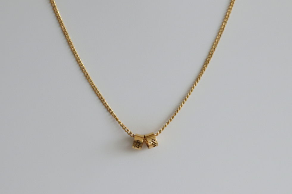 Gold necklace with a small pendant on a light gray background