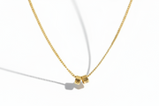 Gold necklace with a small pendant on a white background