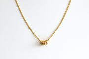 Gold necklace with a small round pendant on a white background