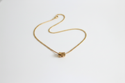 Gold necklace with a cube pendant on a white background