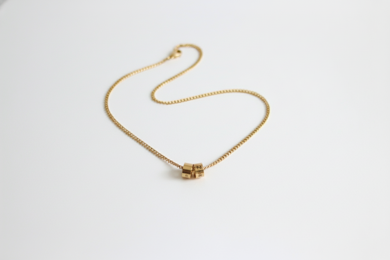 Gold necklace with a cube pendant on a white background
