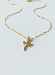 Gold necklace with a dragonfly pendant on a light gray background