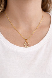 Gold necklace with a hamsa hand pendant on a white background