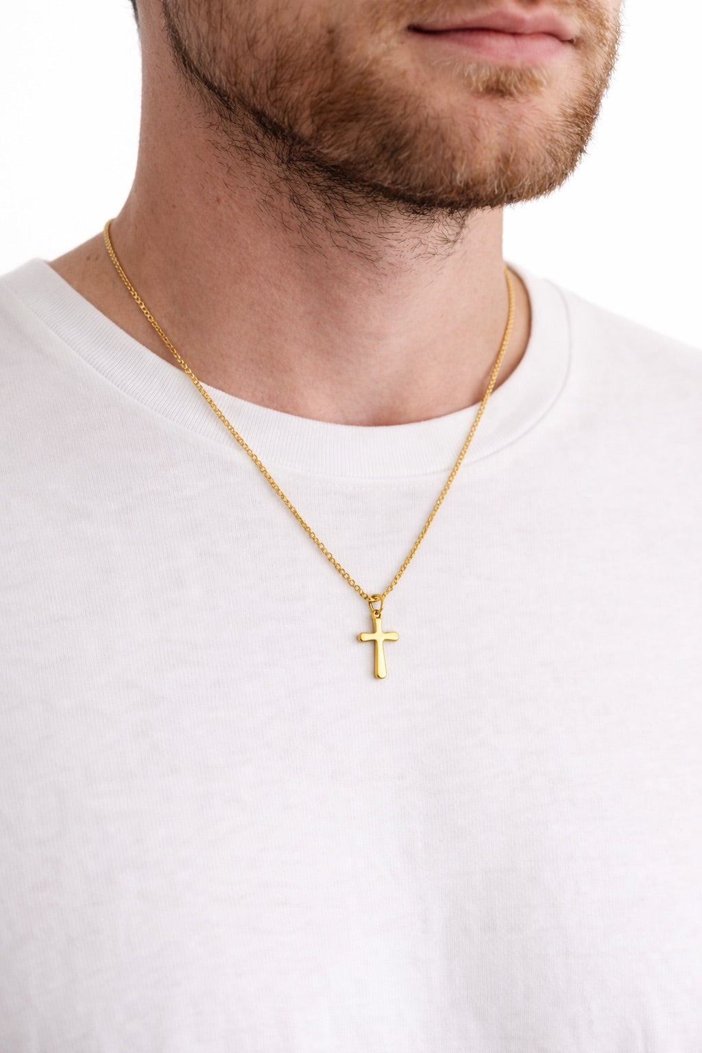 Gold cross chain necklace for men on a white shirt with a plain background