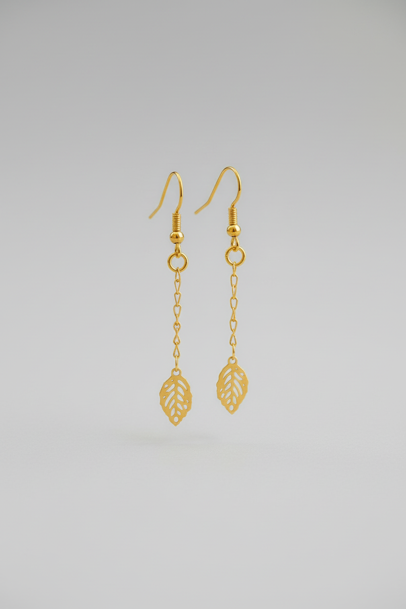 Gold earrings with leaf designs on a light gray background