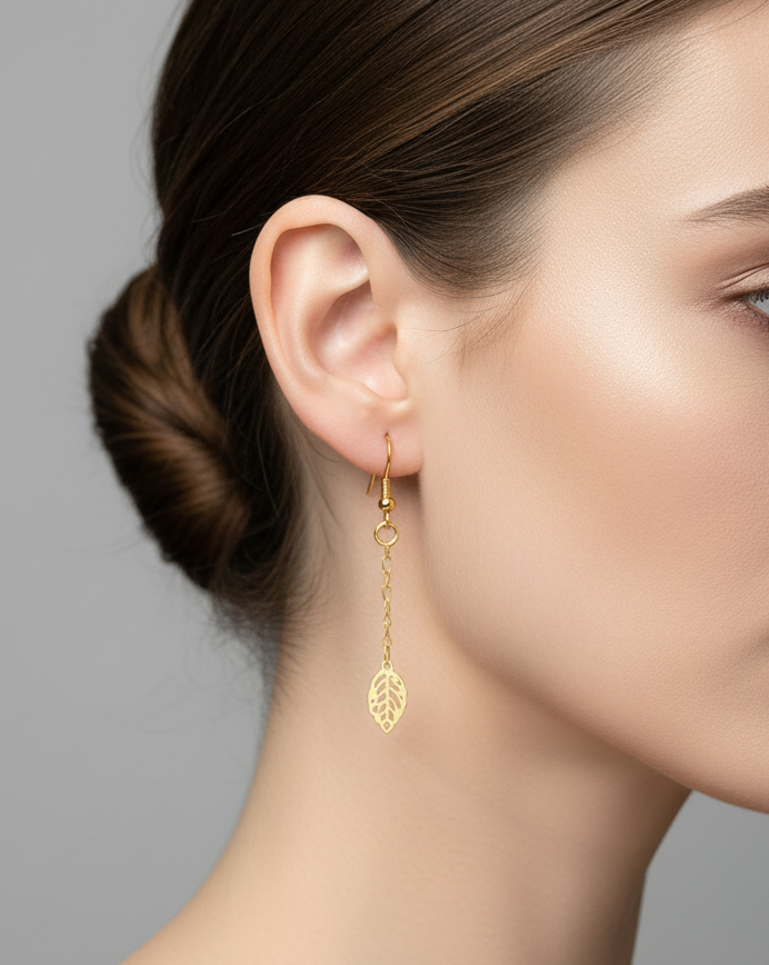 Gold leaf-shaped earring worn by a model on a neutral background