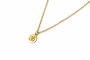 Gold necklace with a round Om pendant on a white background