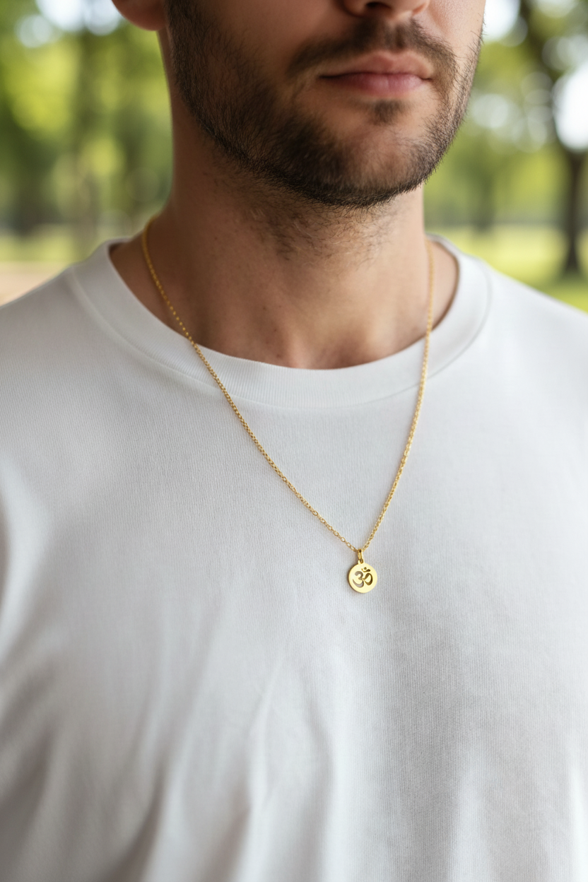 Man wearing a gold necklace with a small om round pendant outdoors