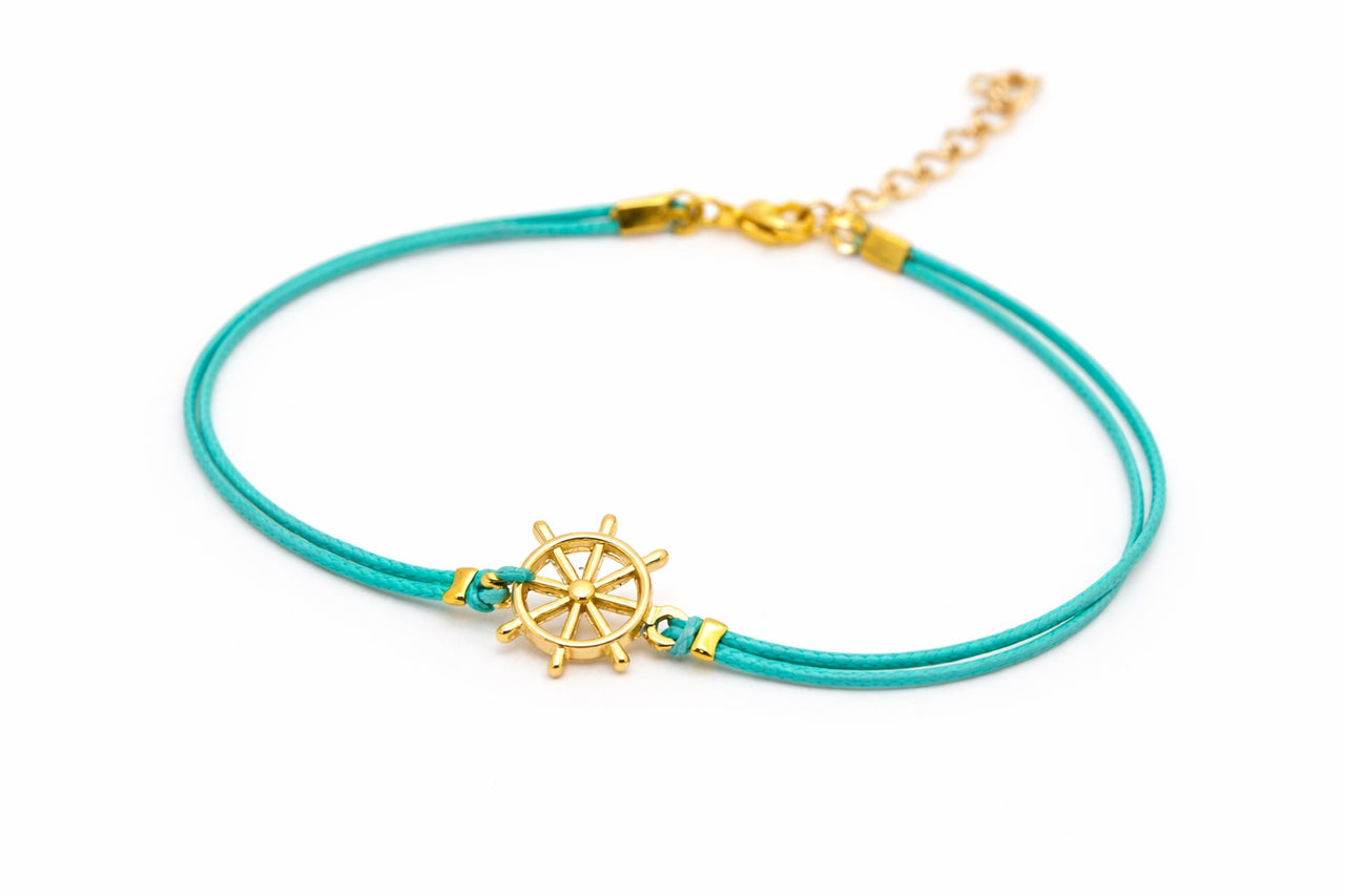 Turquoise ankle bracelet with a gold wheel charm on a white background