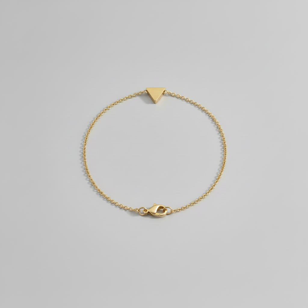 Gold bracelet with a triangle-shaped clasp on a light gray background