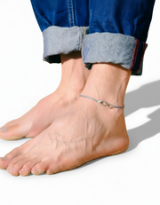 Close-up of a men feet wearing an infinity anklet on a white background
