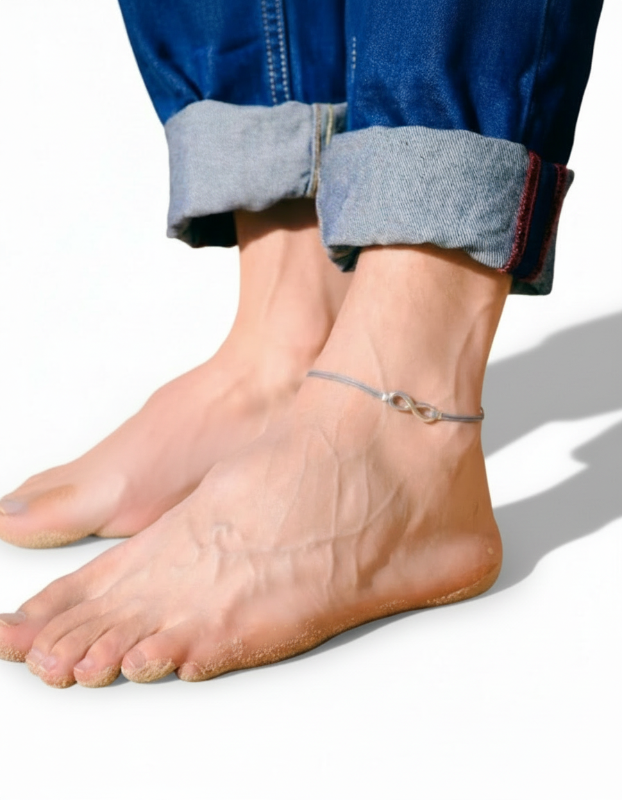 Close-up of a men feet wearing an infinity anklet on a white background