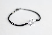Black bracelet with a silver Star of David charm on a light gray background