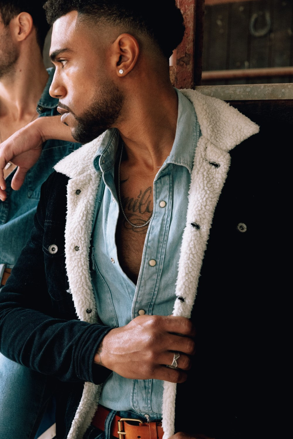 Man outfit wearing blue jacket with white fur a denim button shirt and silver chain necklace and a brown belt