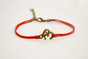 Red bracelet with bronze tone Om charm - shani-adi-jewerly