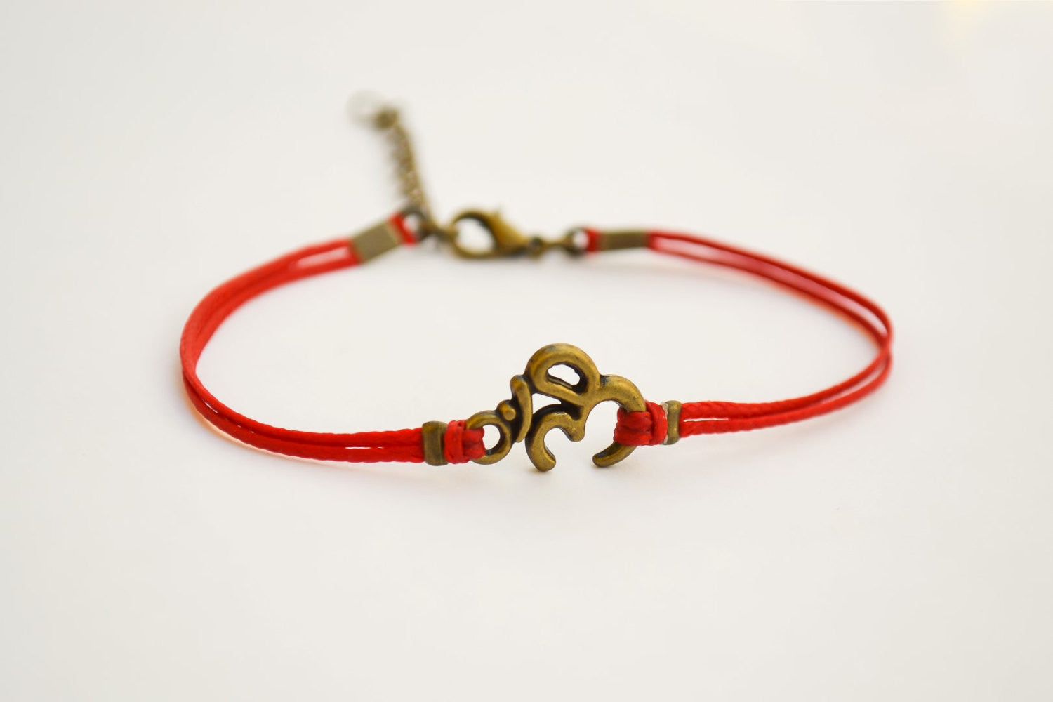 Red bracelet with bronze tone Om charm - shani-adi-jewerly