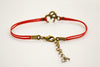 Red bracelet with bronze tone Om charm - shani-adi-jewerly