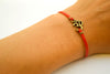 Red bracelet with bronze tone Om charm - shani-adi-jewerly